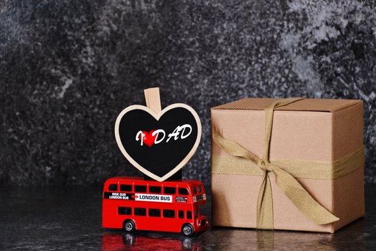 Father's day composition on the dark background. Gift box and london bus with heart. Father's day concept 