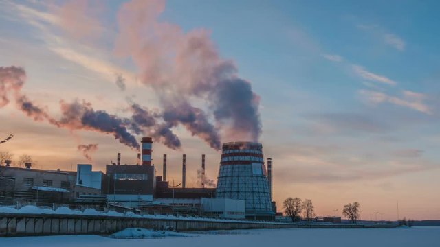 Cogeneration power plant in city. Sunset landscape. Combined heat and power plant near megapolis. Chimney-stalk and ecology problem on Earth. Heat electricity.Time lapses