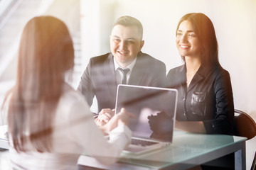 Young couple sitting at a desk in the office of their agent or adviser discussing an investment...