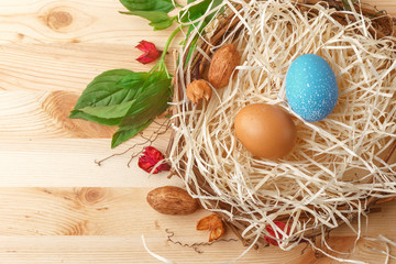 Nest with Easter eggs on wooden background, top view with copy space