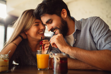 Young couple sharing drink in cafeteria.