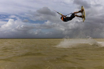 Fototapeta premium Kitesurfer jumps and flies with a kite and a board on water on a sunny day