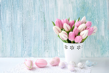 Easter background. Decorative Easter eggs and pink tulips in vase. Copy space