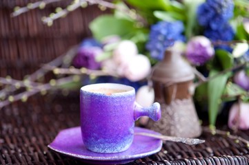 a bouquet of spring flowers in lilac tones and a cup of coffee with cakes