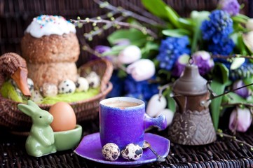 Obraz na płótnie Canvas a bunch of spring flowers in lilac tones, and a cup of coffee with Easter bread and eggs, Easter