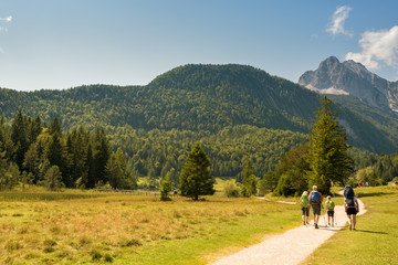Fototapeta na wymiar Alpine valley in summer, road, group of people hiking