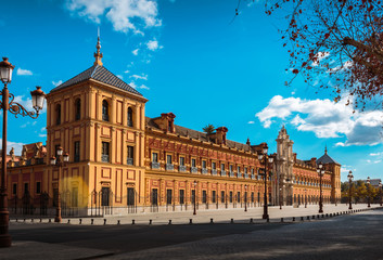 Obraz premium A lovely palace in the middle of Puerta Jerez, a spot in the downtown of Seville, in Andalusia, Spain. With it yellow colour it gives us a contrast with the sky. Beautyful postcard too