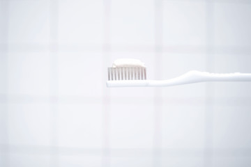 Toothbrush with toothpaste on bathroom background.