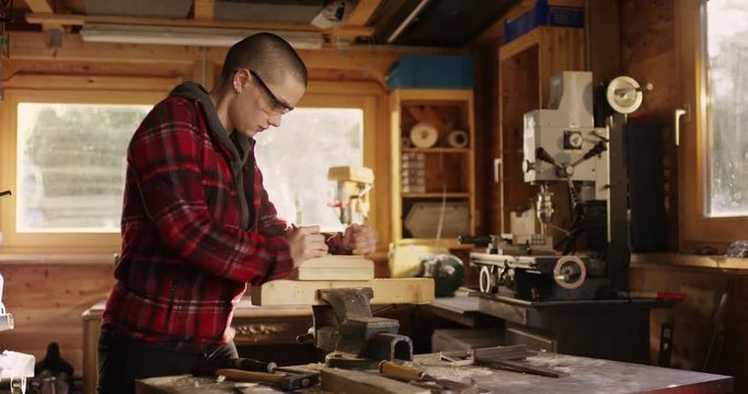 Feminine woman planing pice of wood in workshop