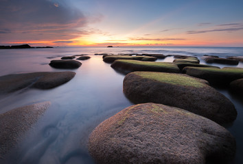 colorful sunset seascape with natural coastal rocks covered by green moss at Kudat Sabah Malaysia. 