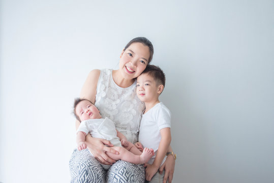 Asian Mother Smiles While Holding Her Little Child And Hug Her Son