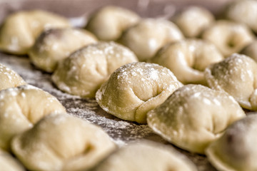 dumplings in raws on a wooden table covered with flour