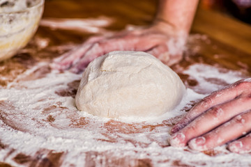 male baker hands kneading dough on wooden table. mass of dough on a table