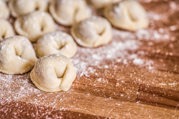 Fototapeta na wymiar homemade raw dumplings on a wooden table covered with flour