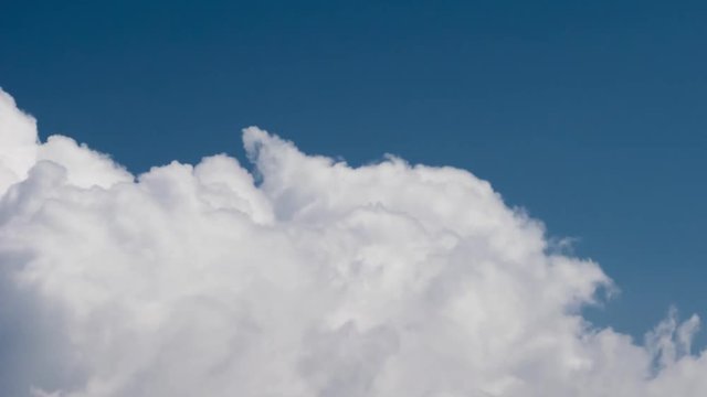Dramatic white cumulus clouds rolling over blue sky background. Timelapse view.