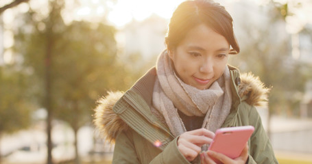 Woman use of mobile phone under sunset time