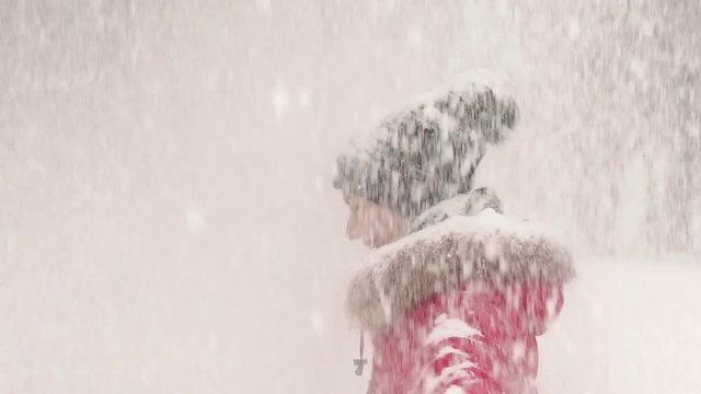 Young woman enjoying winter day outdoors. Happy girl spinning under heavy snow in the Park. Snow winter dream. Slow motion. Happy woman whirls under falling snow stretch out arms, enjoy winter time.
