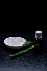 Marine cosmetic salt in a white pial with leaves and aloe on a slate board