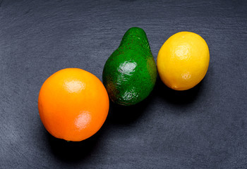 Ripe orange, lemon and avacado on a slate board