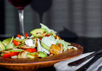 Fresh and appetizing salad of vegetables and a glass of wine on a marble table
