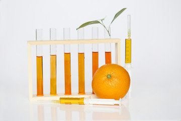 Vitamin C. Medical syringes with a solution of vitamin C, laboratory flasks and fresh orange on a...