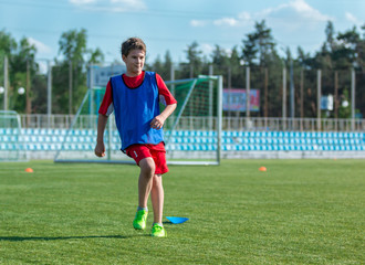 boy trains dribbling on the summer stadium during the training