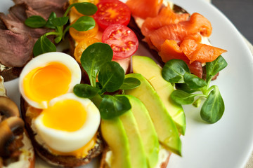 Bruschetta, assorted, different fillings, on plates with a soft-boiled egg in the middle