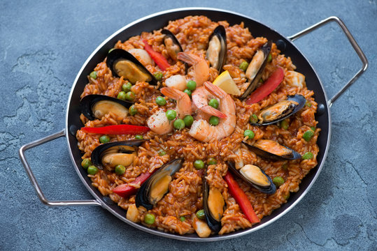Frying pan with spanish traditional paella over blue stone background, studio shot, selective focus
