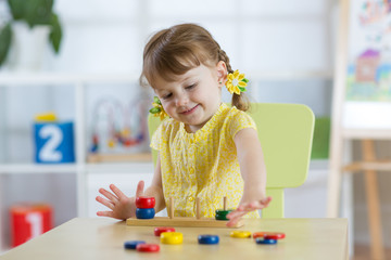 Smart child girl plays in kindergarten in Montessori preschool class.