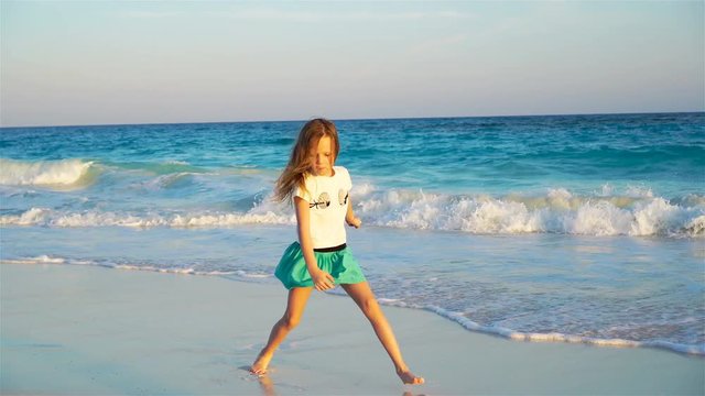 Adorable happy little girl on white beach at sunset