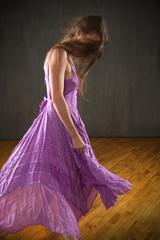 Obraz premium Young woman in lavender dress dancing in the studio.
