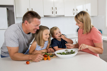 Obraz na płótnie Canvas young attractive couple mother and father preparing salad together with little son and young beautiful daughter in healthy vegetable nutrition