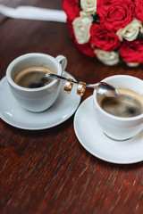 wedding bouquet and coffee with the wedding rings on the table