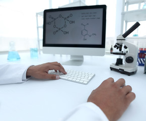 A scientist uses a computer and a microscope
