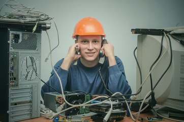 Computer repairman is talking on phone handset and is installing a new computer component. PC...