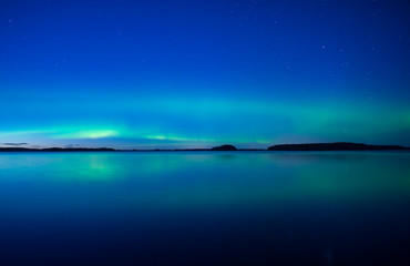 Fototapeta na wymiar Northern lights dancing over calm lake. Farnebofjarden national park in Sweden