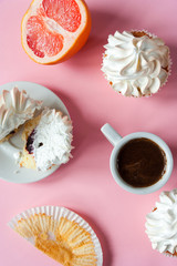   Coffee espresso in a white cup and cakes with meringues on a pink background. Gentle colors. Elegant  dessert. Serving option. Holiday. Wedding table. Sliced grapefruit. Flat lay