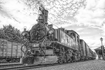 Fototapeta premium Historic steam powered railway train at train station in black and white
