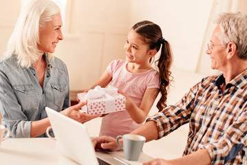 Ive got something for you. Selective focus on a beaming young lady and her excited grandmother looking at each other during a family congratulation.