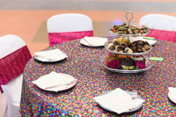 Festive round table covered with colorful tablecloth, decorated with dessert for appetizer in three tier and served with tasty and elegant dishes. Celebration Chinese wedding concept.