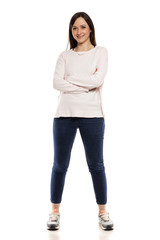 Young woman in jeans, blouse and snekaers on white backgeound