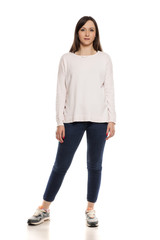 Young woman in jeans, blouse and snekaers on white backgeound