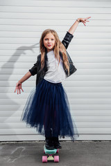 teenage girl on a skateboard against a white wall of a garage door.