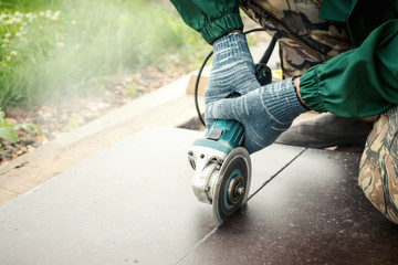 Obraz premium Close-up of worker cutting stone with grinder. Dust while grinding stone pavement