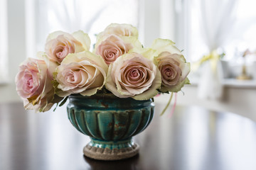 A bouquet of beautiful roses in an vintage vase on the table.