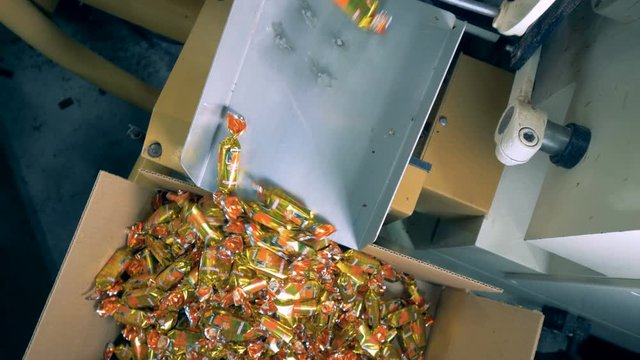 Top view of wrapped up candies being piled up in a box