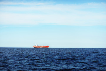 View of a distant red lpg tanker sailing in a open sea on a clear day © Alex Stemmer
