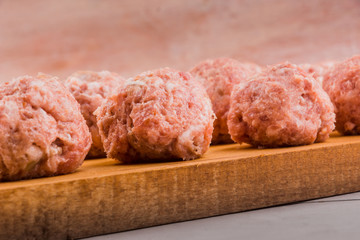 Raw meatballs on a wooden cutting board close up