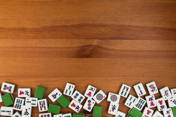 White-green tiles for mahjong on a brown wooden background. Empty space above