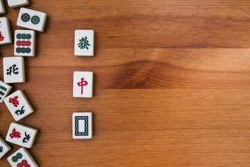 White-green tiles for mahjong on a brown wooden background. Empty place in the center. 3 dragons (red, white, green)